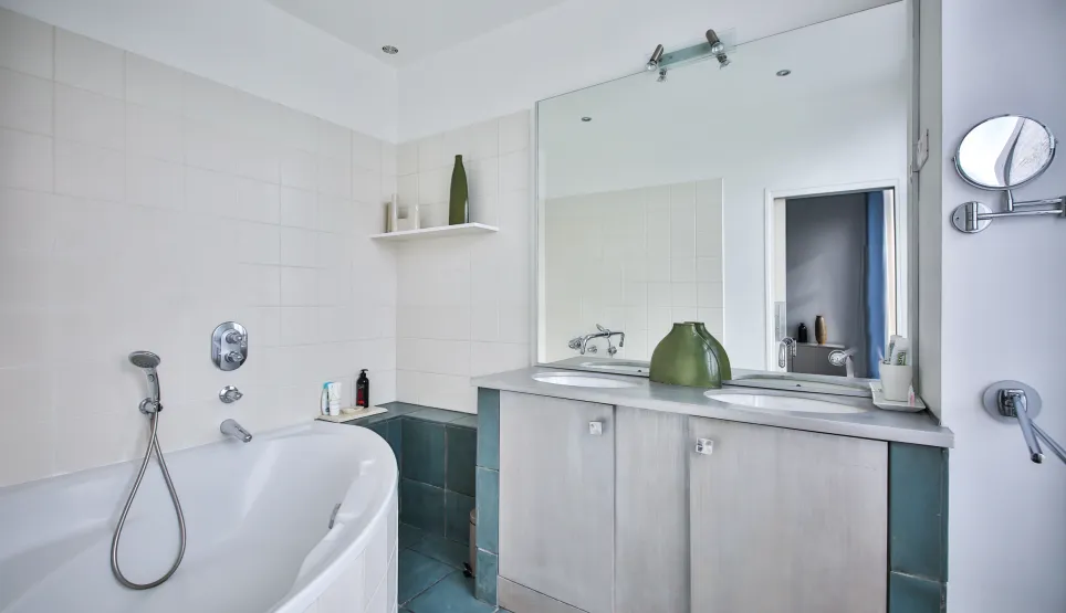 Salle de bain de luxe moderne: baignoire, double vasque, grand miroir, carrelage blanc/bleu. Design épuré, ambiance zen. Idéal propriété haut de gamme.