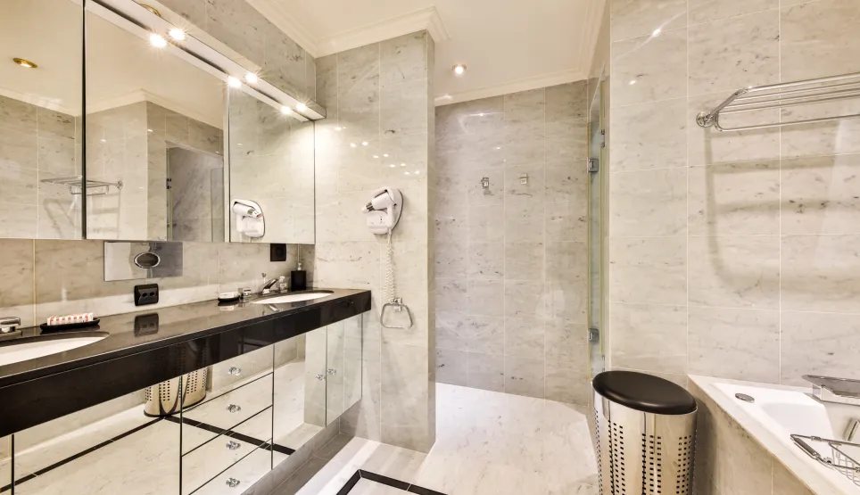 Salle de bain de luxe en marbre. Double vasque, miroir éclairé, douche et baignoire. Design moderne et élégant.