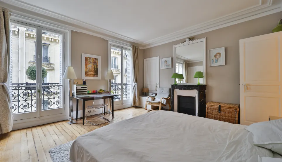 Chambre lumineuse style Haussmannien à Paris. Parquet, cheminée, balcon. Idéal appartement de luxe, charme et élégance.