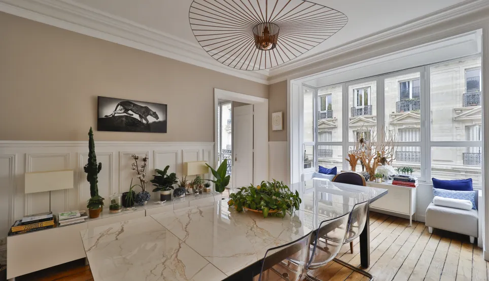 Salle à manger de luxe lumineuse à Paris. Design moderne élégant, grande table marbre, vue imprenable sur architecture haussmannienne.