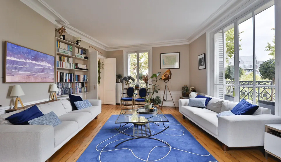 Appartement de luxe: salon spacieux et lumineux, design contemporain, parquet, canapés blancs, tapis bleu. Idéal pour vie urbaine élégante.