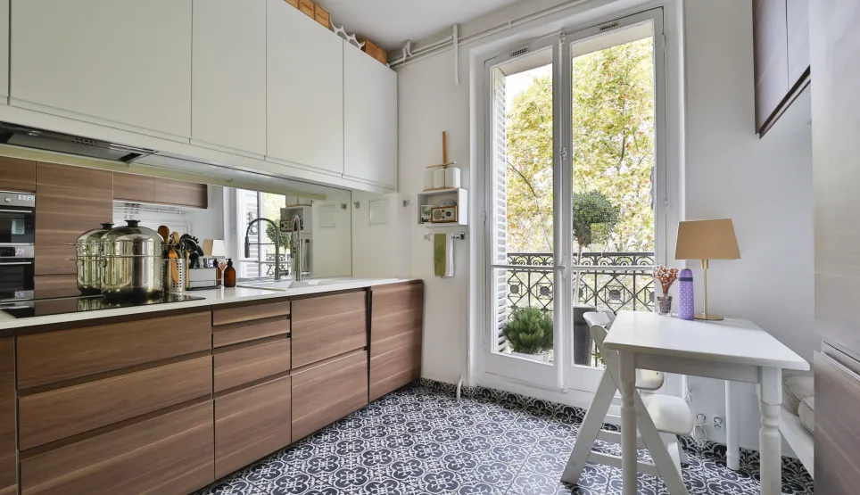 Cuisine de luxe moderne bois/blanc, sol carreaux ciment, balcon. Élégance et fonctionnalité pour appartement de prestige.