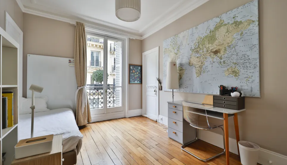 Chambre parisienne élégante, parquet, balcon, bureau. Idéal pour un pied-à-terre de luxe au cœur de Paris.