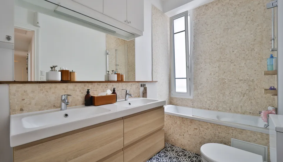 Salle de bain luxe moderne: double vasque bois clair, baignoire, carrelage élégant. Design lumineux, propriété haut de gamme.