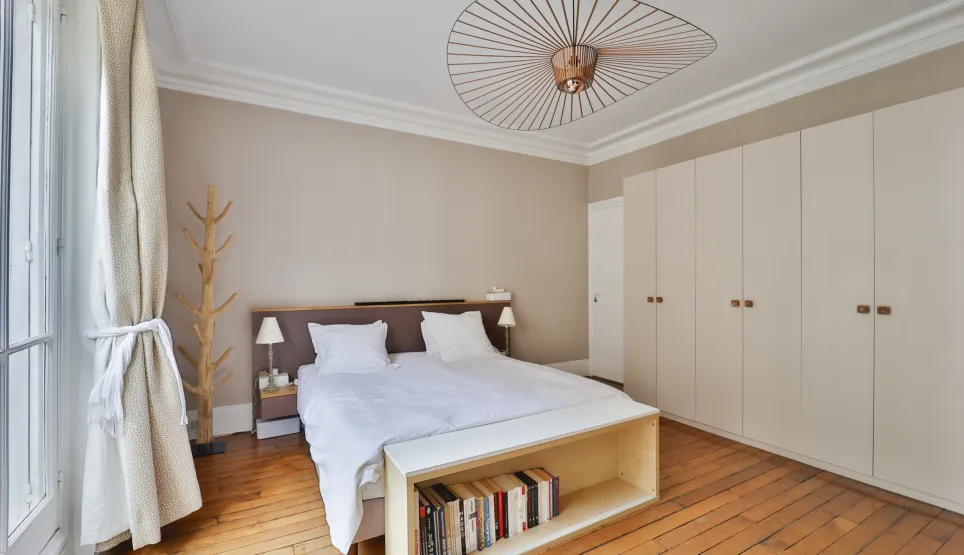 Chambre de luxe moderne et lumineuse avec lit double, parquet, dressing intégré et luminaire design. Idéal pour un appartement élégant.