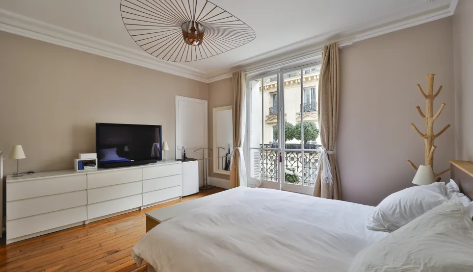 Chambre luxe moderne, balcon, parquet, TV, luminaire design. Intérieur élégant et lumineux.