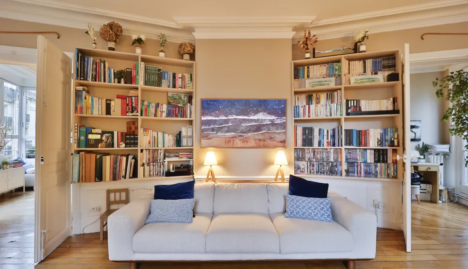 Salon lumineux et raffiné avec bibliothèques intégrées, canapé design et œuvre d'art. L'élégance d'un intérieur de luxe.