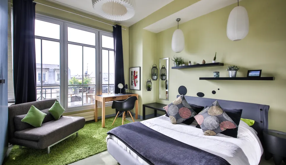 Chambre moderne et lumineuse avec vue ville, design contemporain, lit confortable, espace bureau et coin détente. Idéal appartement de luxe.