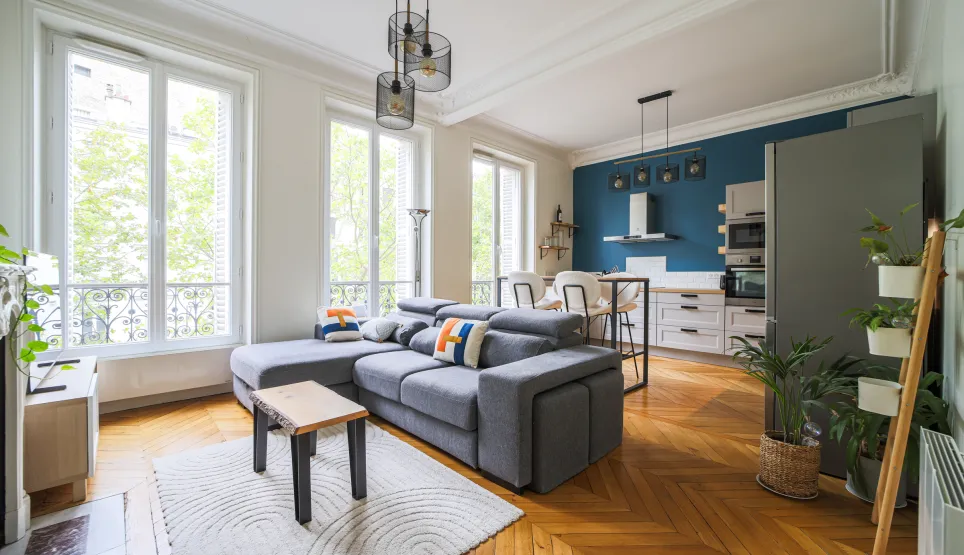 Magnifique appartement de luxe avec salon-cuisine ouvert, parquet chevron, grandes fenêtres lumineuses. Design moderne et élégant.