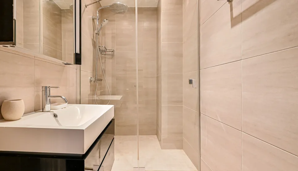 Salle de bain contemporaine: douche à l'italienne, lavabo design, carrelage clair. Ambiance zen et luxe pour propriété d'exception.