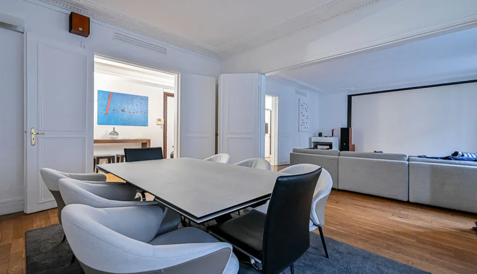 Salle à manger design ouverte sur salon home cinéma. Intérieur luxe moderne et spacieux avec parquet. Élégance et confort.