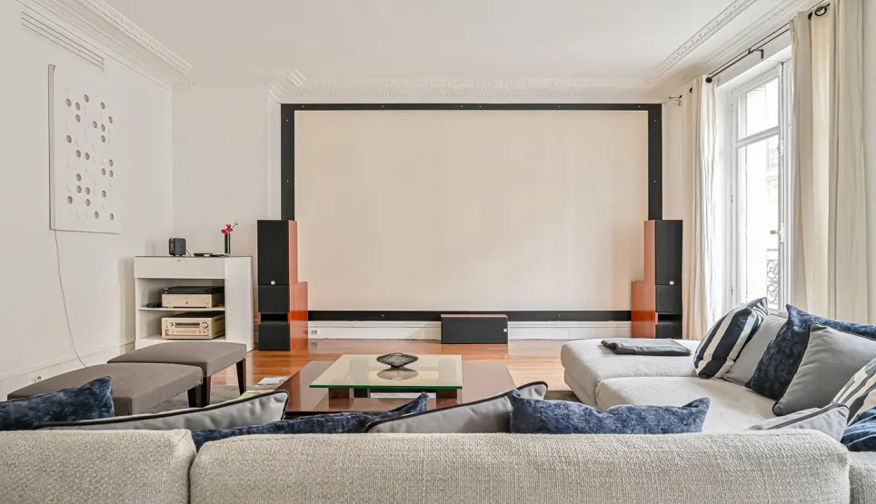 Salon de luxe avec home cinéma intégré, grand écran de projection, canapés confortables. Idéal pour divertissement haut de gamme et soirées film.
