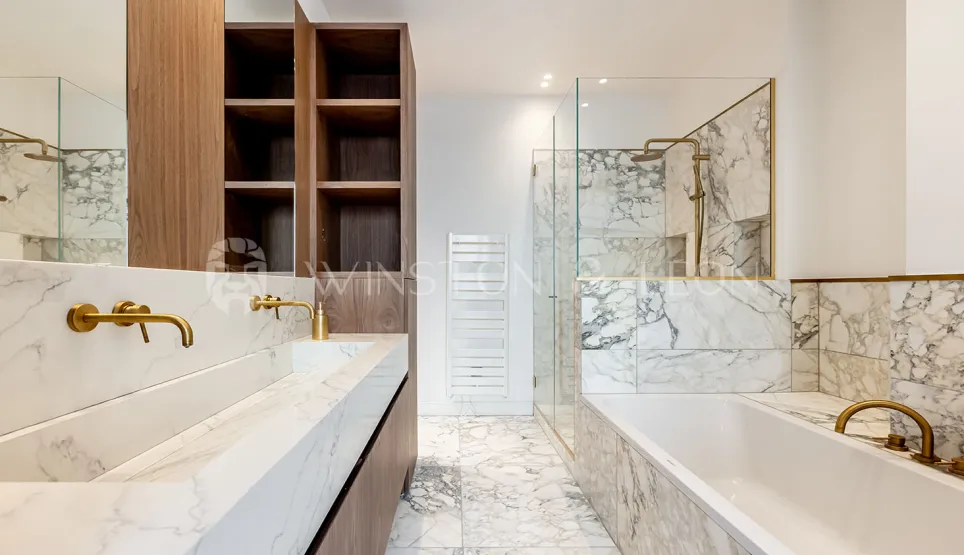 Salle de bain de luxe moderne : marbre blanc, double vasque, robinetterie dorée, douche à l'italienne et baignoire. Design élégant.
