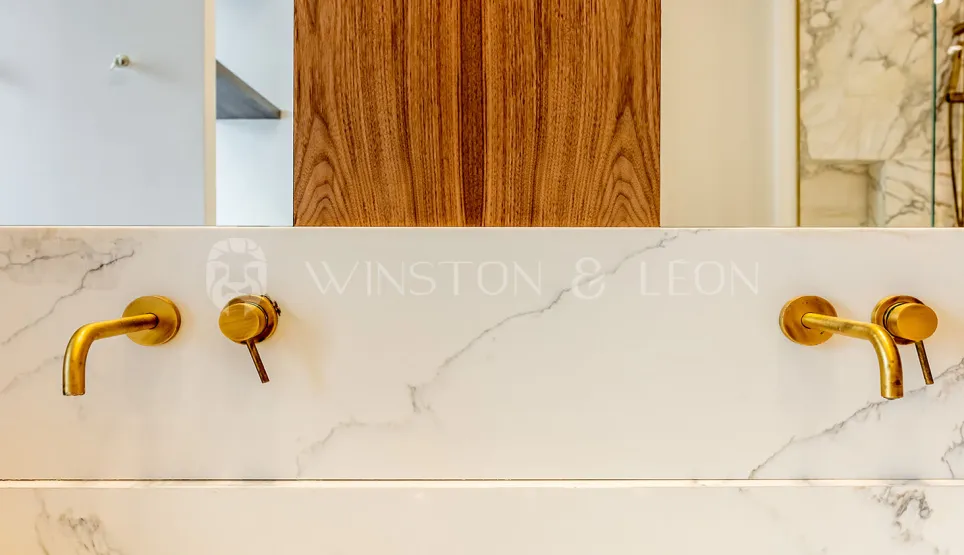 Salle de bain luxe: robinetterie laiton murale sur marbre blanc veiné. Design contemporain élégant. Winston & Leon.
