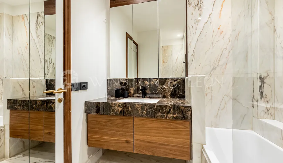 Salle de bain de luxe moderne. Marbre veiné clair et foncé, meuble vasque en bois élégant et grand miroir. Design intérieur haut de gamme.