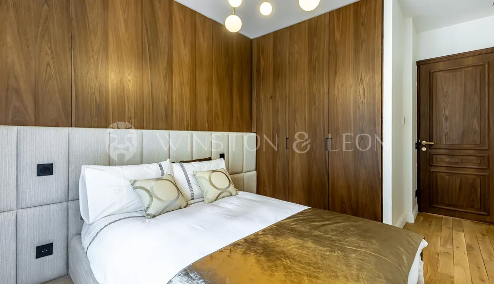 Chambre de luxe moderne avec boiseries murales élégantes, lit confortable et tête de lit capitonnée. Design raffiné pour suite parentale.