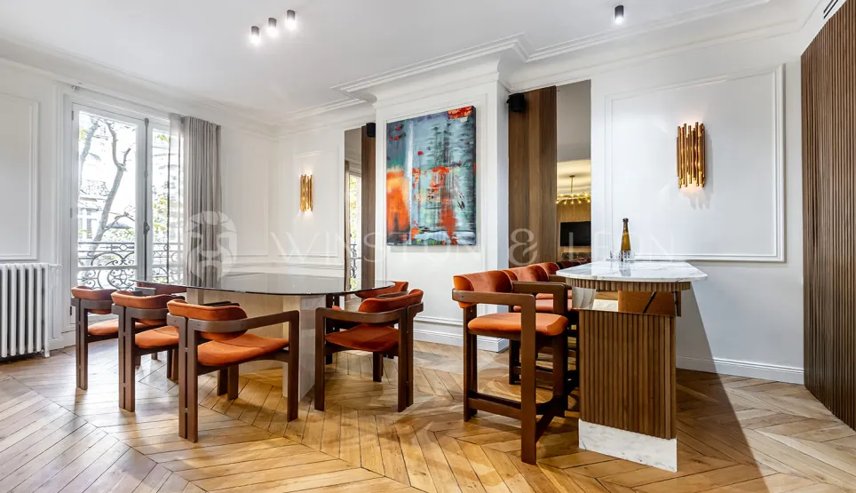 Appartement de luxe : salle à manger et bar design, parquet chevrons, art moderne. Espace élégant et lumineux pour recevoir.