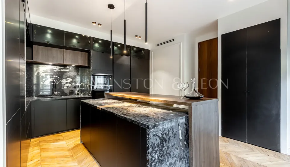 Cuisine de luxe contemporaine noire, îlot marbre, bois, parquet. Design élégant et sophistiqué pour un intérieur haut de gamme.