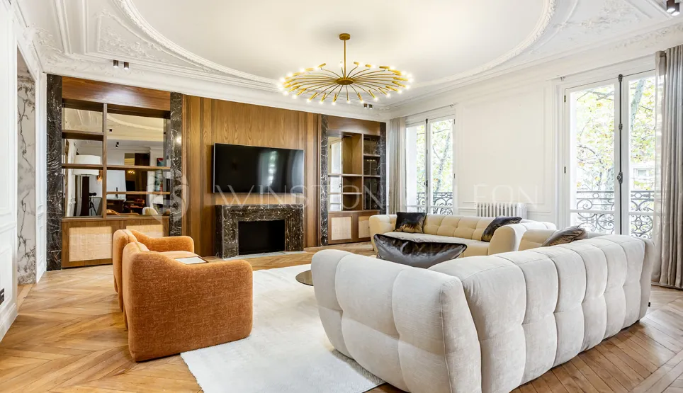 Superbe salon de luxe: design moderne, cheminée marbre, parquet, moulures, canapés design. Ambiance lumineuse et raffinée pour appartement parisien.