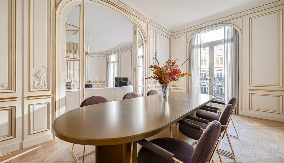 Salle à manger de luxe parisienne: moulures dorées, parquet, design contemporain. Élégance et prestige pour un appartement d'exception.