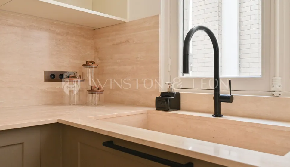 Cuisine luxe: évier intégré pierre naturelle, robinet noir mat, plan de travail élégant. Ambiance moderne et épurée.