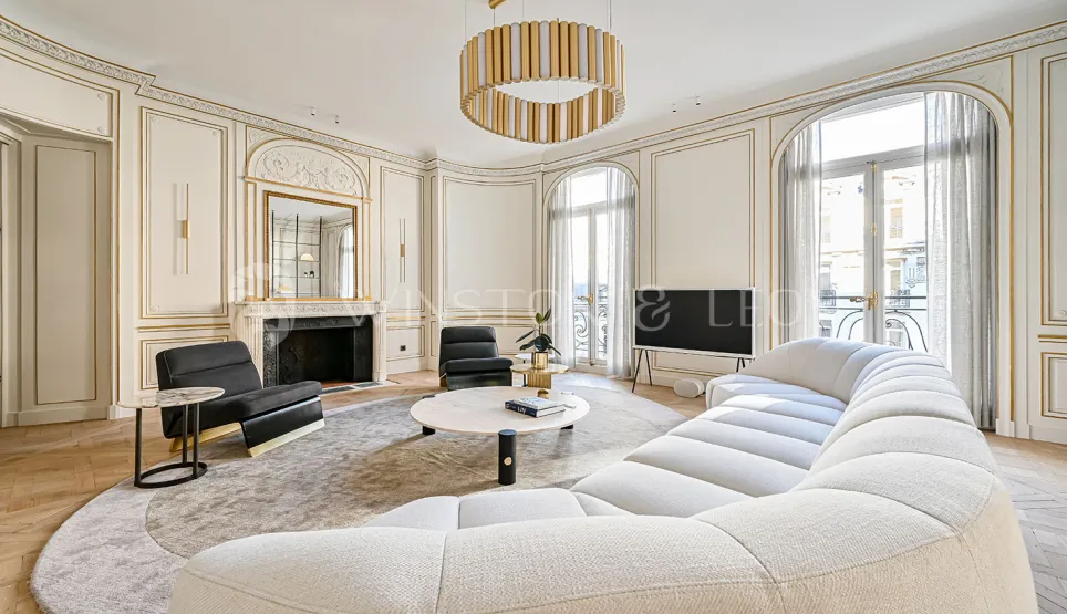 Salon de luxe parisien. Design moderne et classique Haussmannien, moulures dorées, canapé contemporain. Élégance et raffinement.