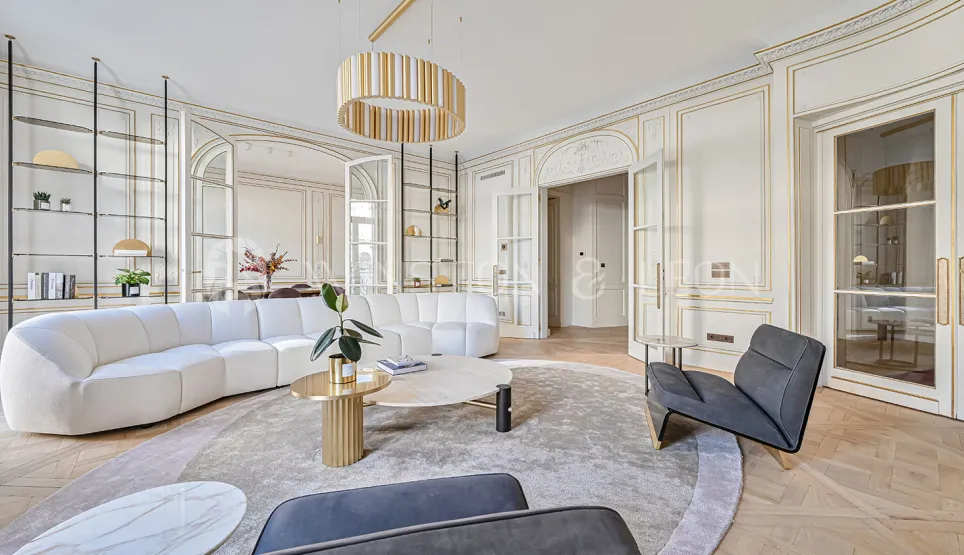 Salon de luxe contemporain, moulures dorées, canapé design, parquet chevrons. Élégance parisienne lumineuse et raffinée.