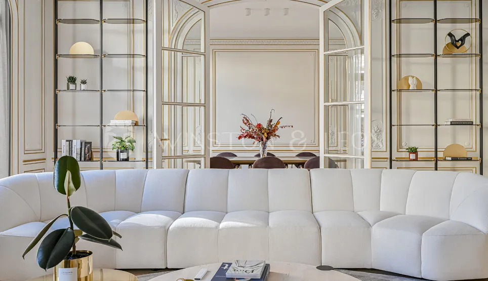 Élégant salon de luxe, canapé blanc moderne, moulures dorées. Ambiance chic et raffinée pour un appartement haussmannien d'exception.