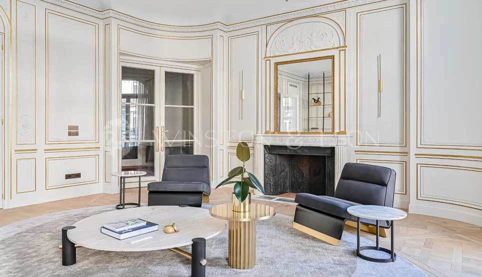 Luxueux salon parisien Haussmannien. Moulures dorées, cheminée, mobilier design contemporain. Élégance et raffinement intemporels.