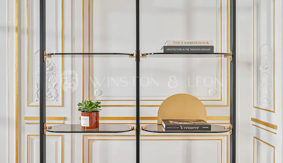 Étagère design luxe en verre et métal noir, accents or, sur fond de boiseries classiques haussmanniennes. Élégance et raffinement contemporain.