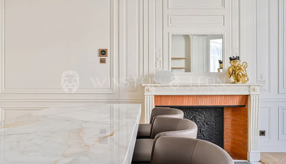 Intérieur luxe parisien: table marbre, cheminée classique, moulures. Élégance intemporelle pour propriété haut de gamme.