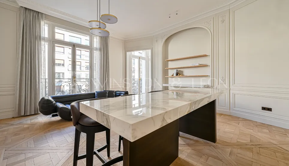 Appartement de luxe Parisien avec cuisine ouverte design, îlot en marbre, parquet chevron et moulures. Élégance et modernité.