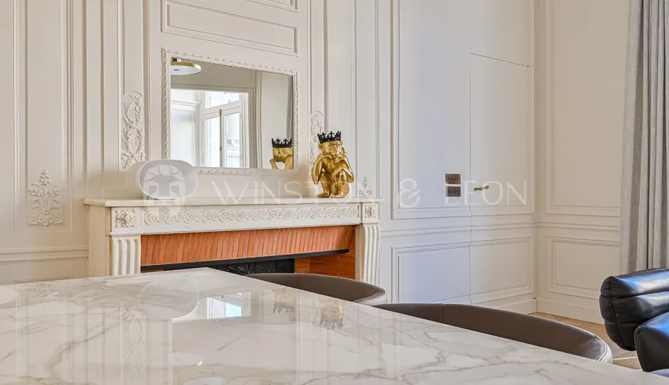 Élégant intérieur Haussmannien: boiseries, cheminée ornée, miroir, table marbre. Luxe parisien raffiné, design chic.