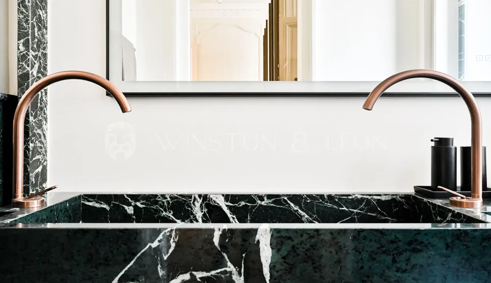 Salle de bain de luxe: double vasque en marbre vert, robinetterie cuivre design. Élégance moderne pour un intérieur raffiné.