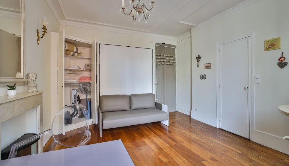 Studio de luxe optimisé avec canapé convertible, parquet, moulures et rangements intégrés. Élégance et fonctionnalité à Paris.