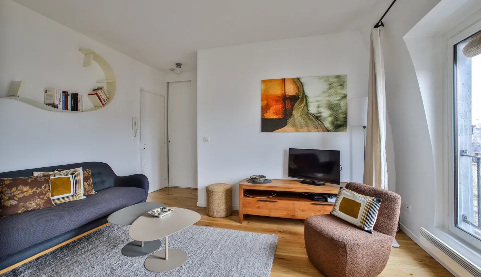 Salon moderne et lumineux avec mobilier design, art contemporain et parquet. Ambiance raffinée pour un appartement de luxe parisien.