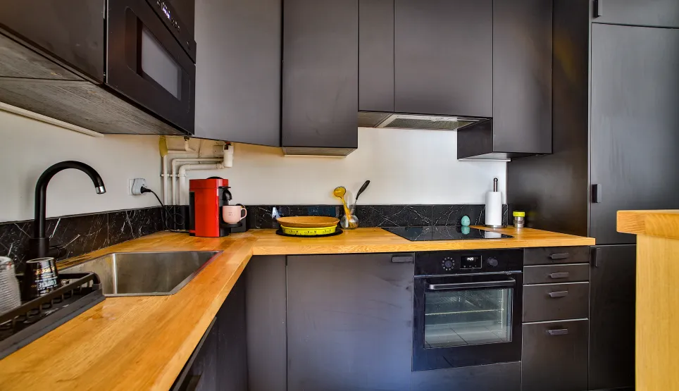 Cuisine design luxe: meubles noirs mats, plan de travail bois clair, équipée. Élégance contemporaine.
