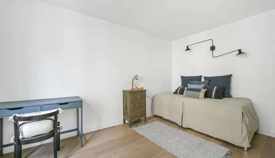 Chambre/bureau minimaliste et lumineux. Parquet clair, lit design, bureau élégant. Espace polyvalent raffiné pour propriété de luxe.