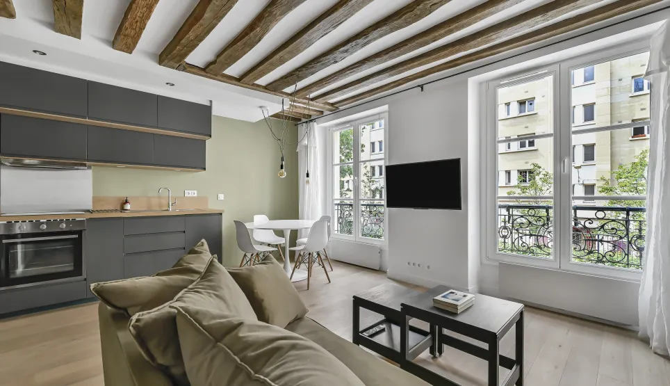 Appartement de luxe rénové, salon-cuisine ouvert, poutres apparentes, design moderne, lumineux. Idéal investissement Paris.