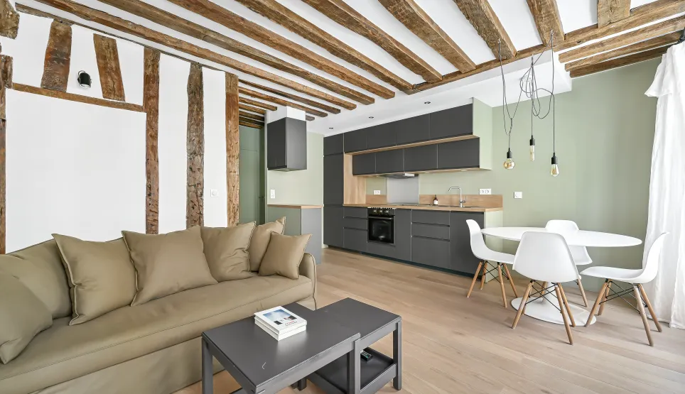 Appartement de luxe avec poutres apparentes, cuisine moderne ouverte et salon élégant. Design contemporain, parquet clair.