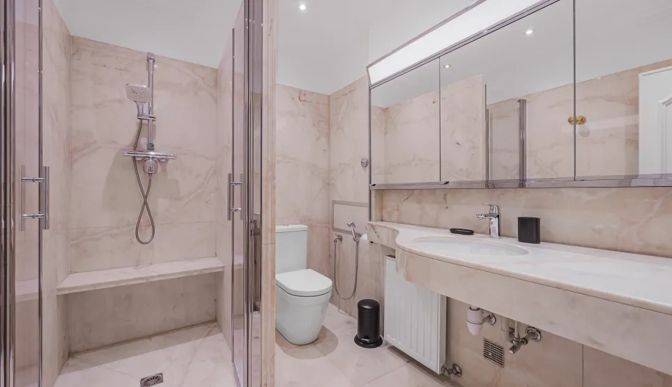 Salle de bain de luxe en marbre. Douche à l'italienne avec banc, WC design, double vasque. Élégance et confort haut de gamme.