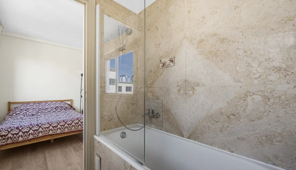 Découvrez cette suite moderne: salle de bain avec baignoire, douche et murs en pierre naturelle, ouverte sur une chambre lumineuse. Luxe fonctionnel.