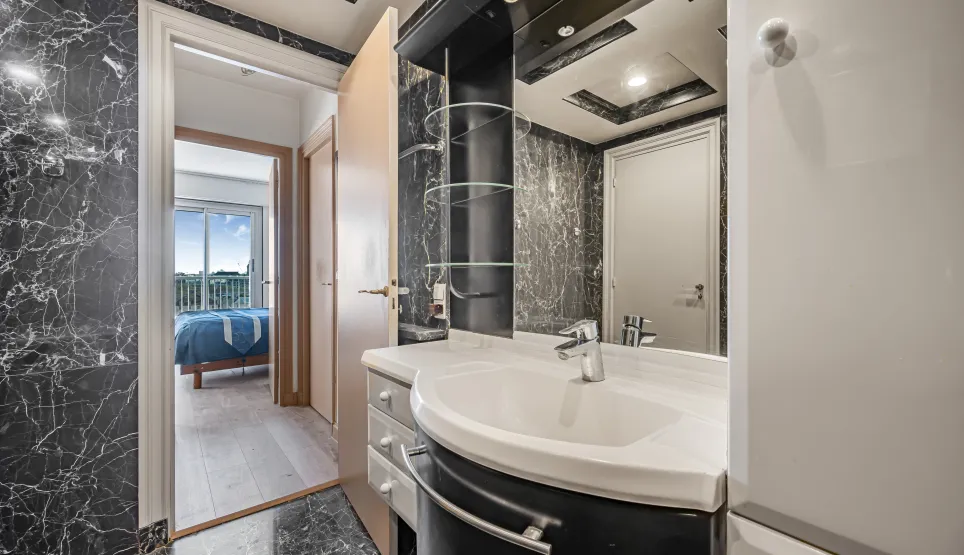 Salle de bain élégante en marbre noir, design moderne avec vasque intégrée. Accès suite parentale lumineuse avec vue. Luxe et confort.