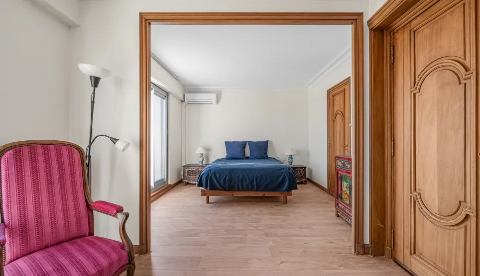 Suite parentale lumineuse et élégante avec lit double bleu, parquet bois clair et mobilier raffiné. Un intérieur de charme pour propriété de luxe.