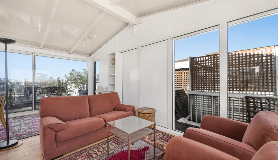 Salon lumineux penthouse avec vue terrasse, grandes baies vitrées. Appartement de luxe, espace moderne et confortable. Idéal vie urbaine.