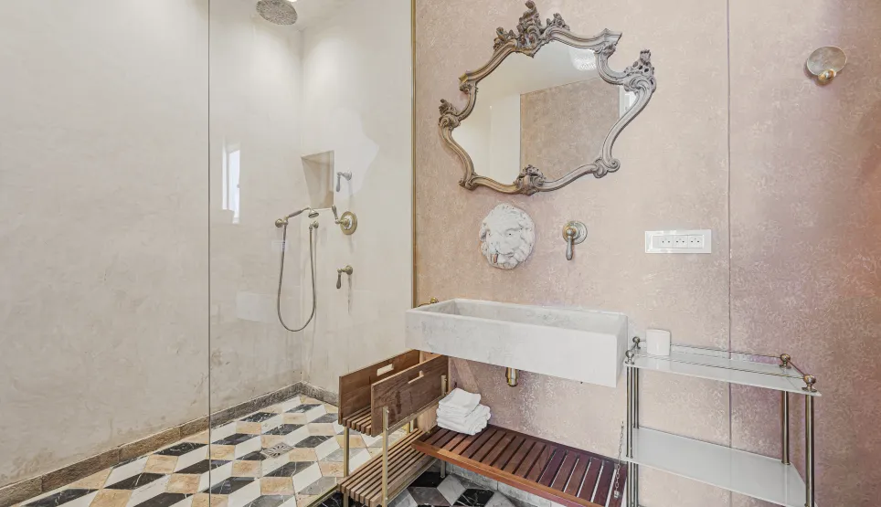 Salle de bain de luxe. Douche vitrée, miroir baroque, lavabo en pierre, sol marbre géométrique. Design élégant et raffiné.