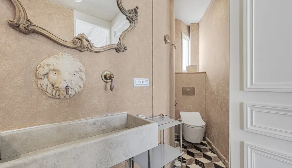 Luxueuse salle d'eau: miroir baroque, lavabo pierre, robinet tête de lion. Design élégant, carrelage géométrique. Intérieur chic et raffiné.