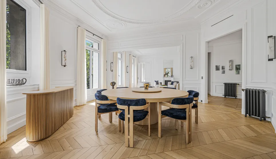Salle à manger de luxe lumineuse, design élégant. Appartement parisien avec parquet chevrons, moulures. Raffinement et espace.