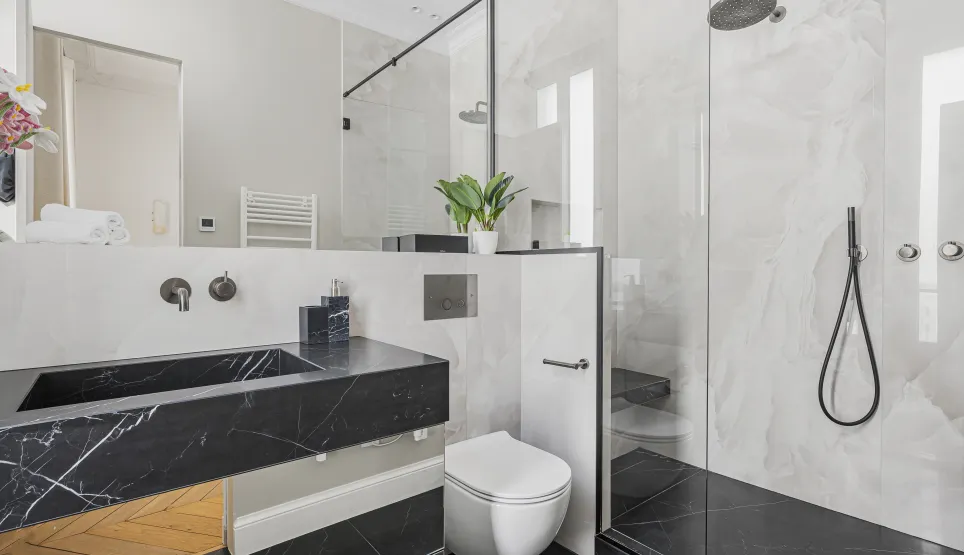 Salle de bain luxe marbre noir et blanc. Douche à l'italienne, lavabo design. Élégance contemporaine pour propriété haut de gamme.