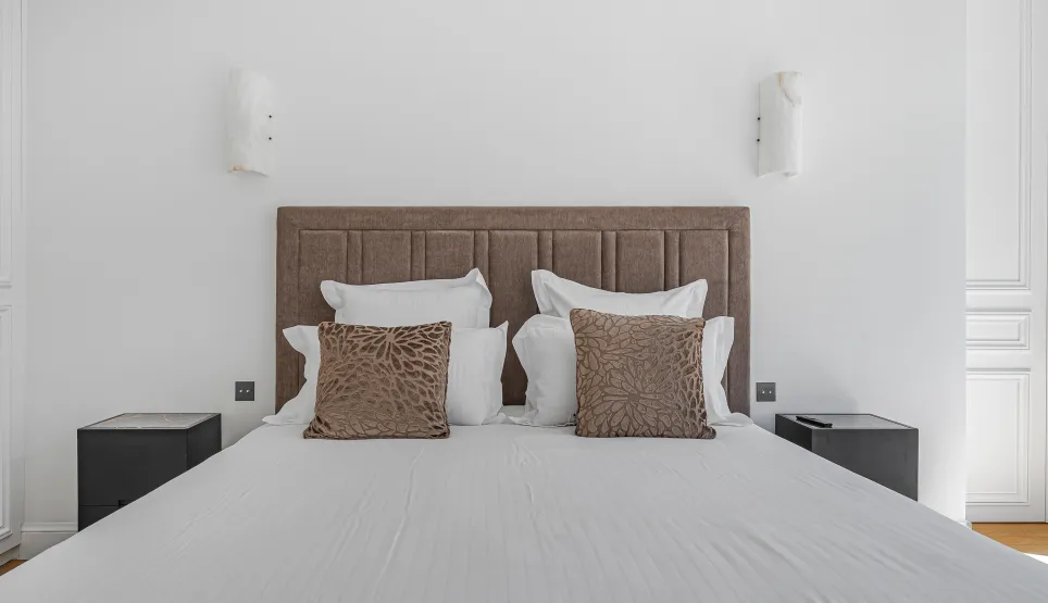 Chambre parentale de luxe, lit double confortable avec tête de lit capitonnée, décoration moderne et élégante. Idéal pour un appartement haut de gamme.